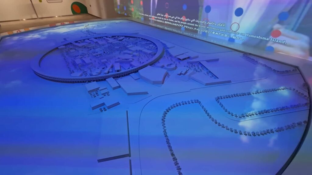 A detailed architectural model showcased on a blue-lit interactive table