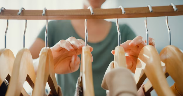 Hands sort through hangers with clothes